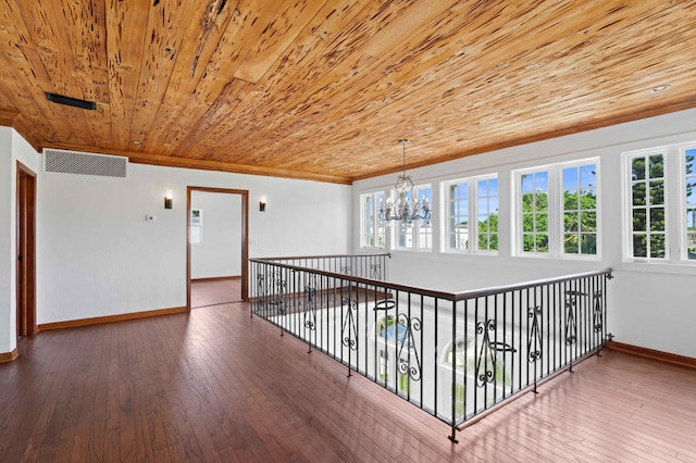 corridor with hardwood / wood-style floors, ornamental molding, wooden ceiling, and a notable chandelier