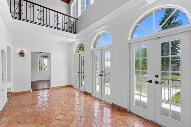 tiled foyer entrance featuring a wealth of natural light, french doors, and a towering ceiling