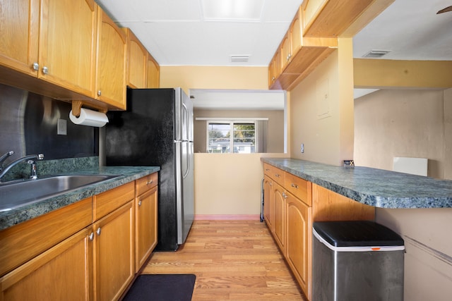 kitchen featuring stainless steel fridge, sink, and light wood-type flooring