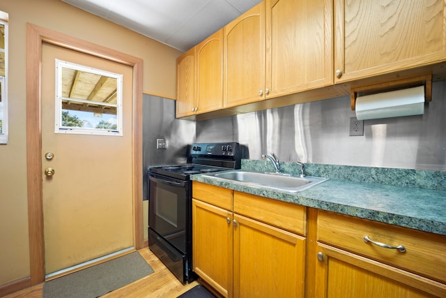 kitchen featuring black range with electric cooktop, light wood-type flooring, and sink