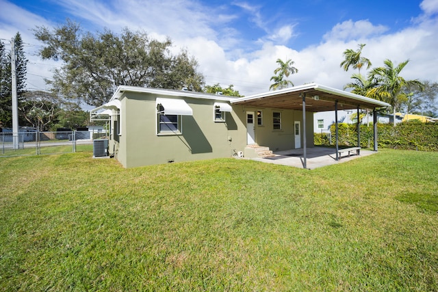 rear view of property with a lawn, central AC unit, and a patio