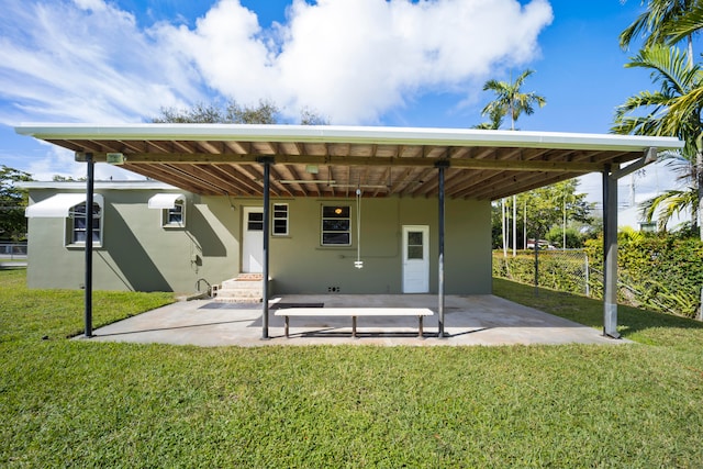 back of property with a carport and a yard