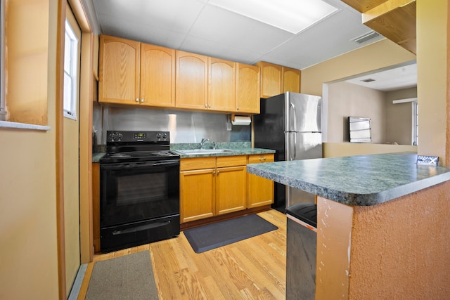 kitchen with light hardwood / wood-style floors, black range with electric stovetop, kitchen peninsula, stainless steel fridge, and sink