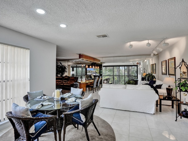 dining room with rail lighting, a textured ceiling, and light tile floors