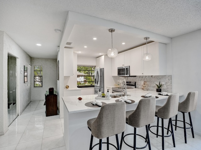 kitchen featuring light tile floors, kitchen peninsula, appliances with stainless steel finishes, hanging light fixtures, and sink