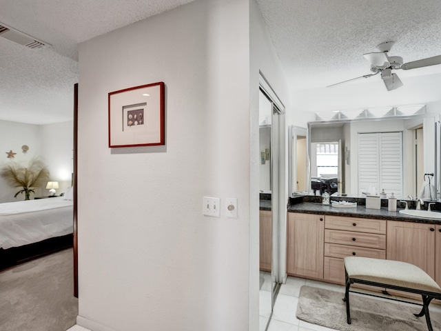 bathroom featuring tile floors, ceiling fan, and a textured ceiling