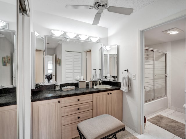 full bathroom featuring toilet, ceiling fan, vanity with extensive cabinet space, tile floors, and bath / shower combo with glass door