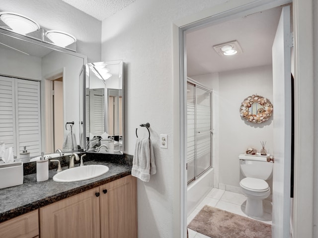 full bathroom with toilet, tile flooring, shower / bath combination with glass door, a textured ceiling, and vanity