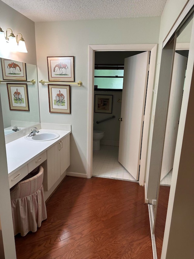 bathroom featuring toilet, a textured ceiling, vanity, and hardwood / wood-style flooring