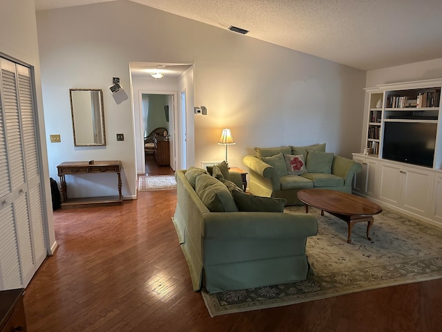 living room with dark hardwood / wood-style floors, a textured ceiling, and vaulted ceiling