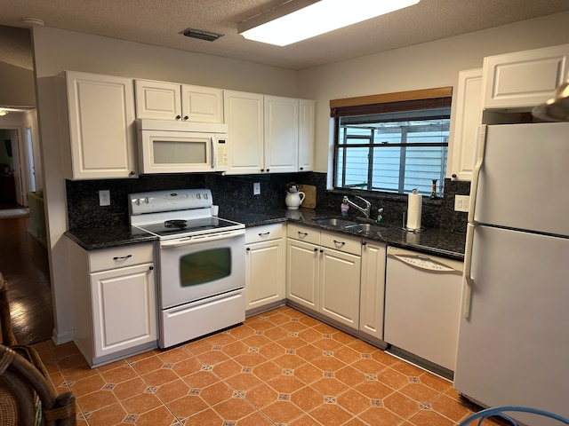 kitchen with light tile floors, white appliances, white cabinets, backsplash, and sink