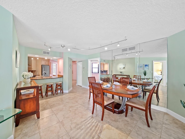 tiled dining space featuring a textured ceiling and rail lighting