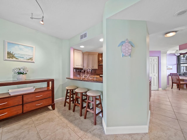 kitchen with light tile floors, tasteful backsplash, ceiling fan, and a breakfast bar