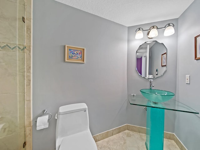 bathroom with toilet, sink, a shower, tile flooring, and a textured ceiling