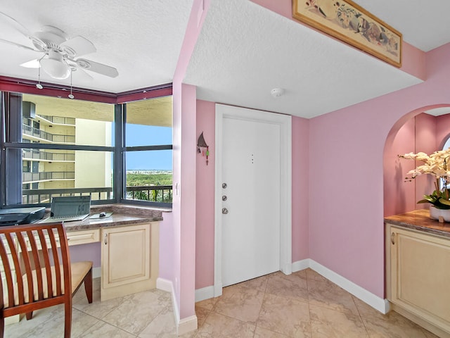 tiled entryway with a textured ceiling and ceiling fan