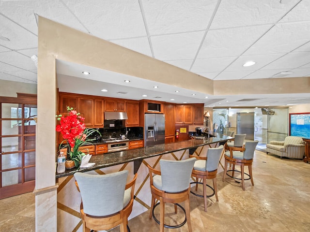 kitchen with stainless steel appliances, light tile floors, and a kitchen breakfast bar