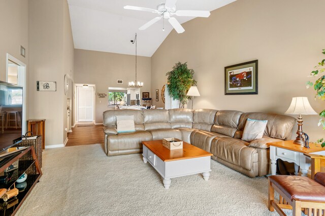 living room featuring high vaulted ceiling, ceiling fan with notable chandelier, and light colored carpet