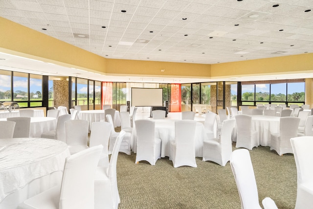 dining space featuring a drop ceiling and dark carpet