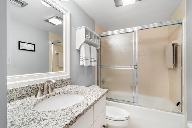 full bathroom featuring vanity, bath / shower combo with glass door, and toilet