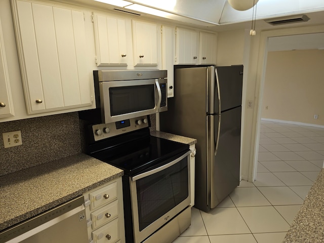 kitchen with white cabinets, appliances with stainless steel finishes, tasteful backsplash, and light tile flooring