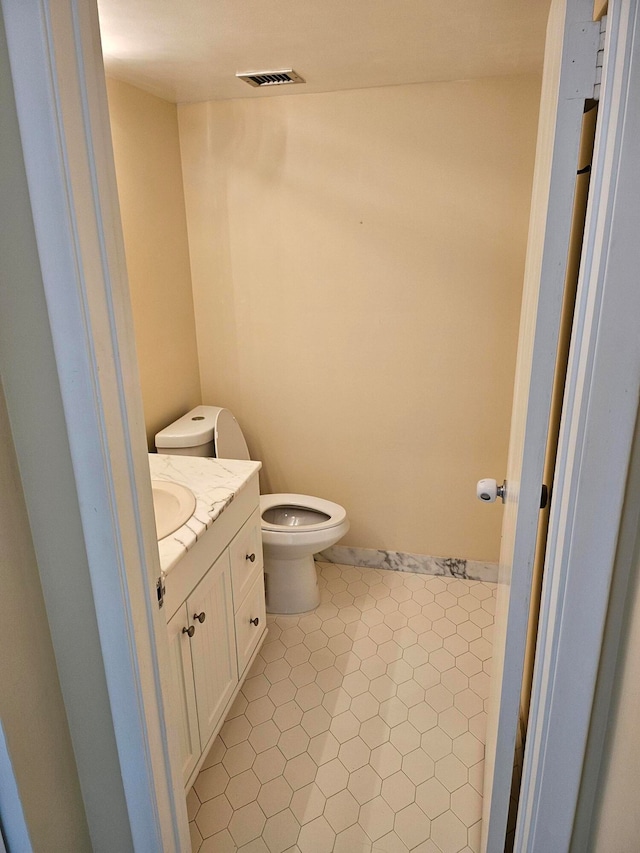 bathroom with toilet, tile flooring, and vanity