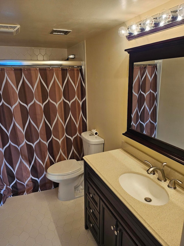 bathroom featuring toilet, vanity with extensive cabinet space, and tile flooring