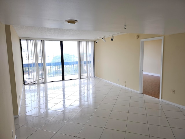 tiled empty room with track lighting and expansive windows