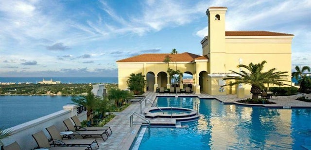 view of pool with a water view, a patio, and a hot tub