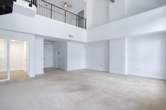 spare room with light carpet, ceiling fan, and a towering ceiling