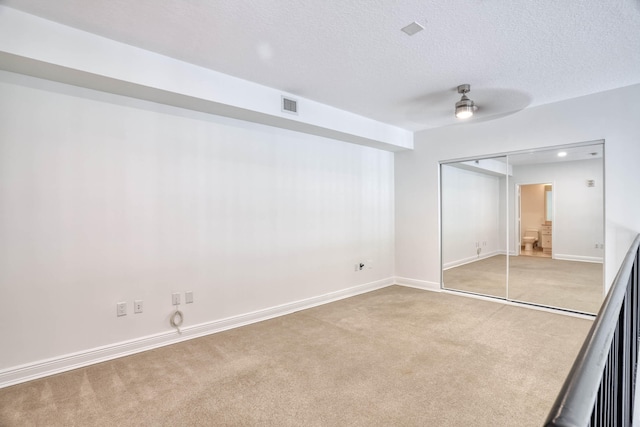 unfurnished room featuring light carpet, a textured ceiling, and ceiling fan