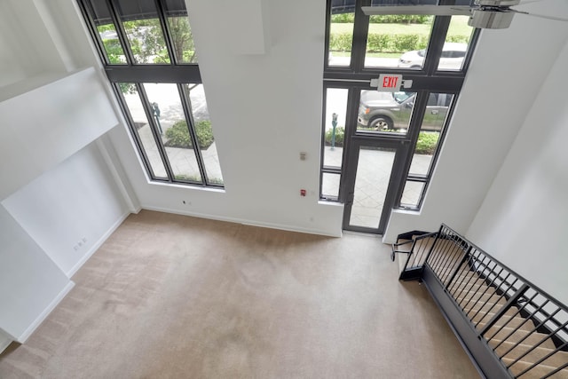 foyer featuring a high ceiling, light carpet, and ceiling fan