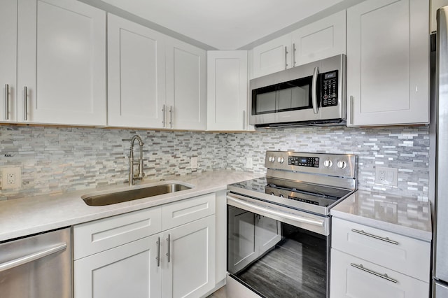 kitchen with backsplash, appliances with stainless steel finishes, sink, and white cabinets