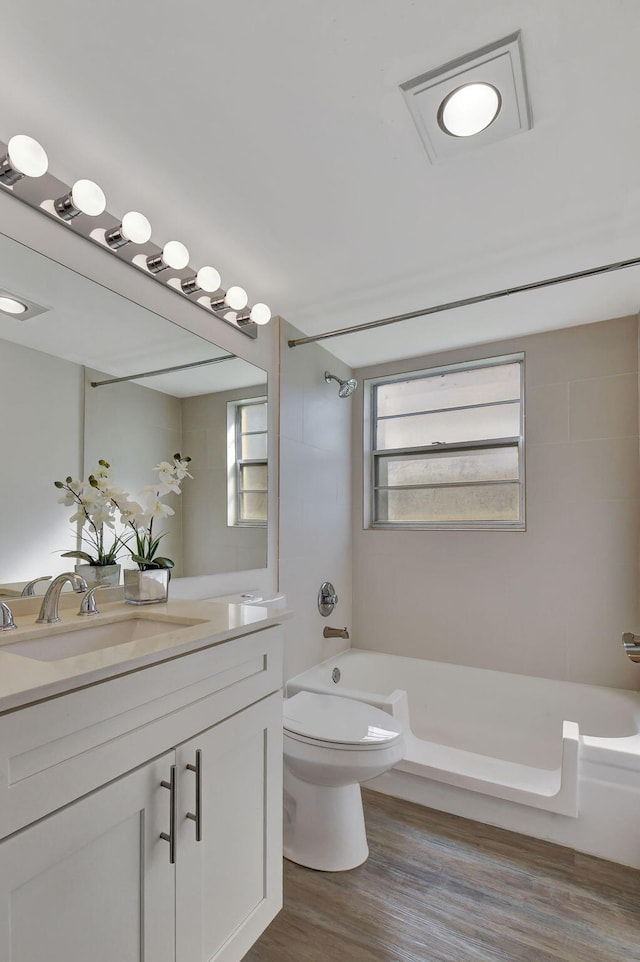 full bathroom with toilet, tiled shower / bath combo, hardwood / wood-style flooring, and vanity