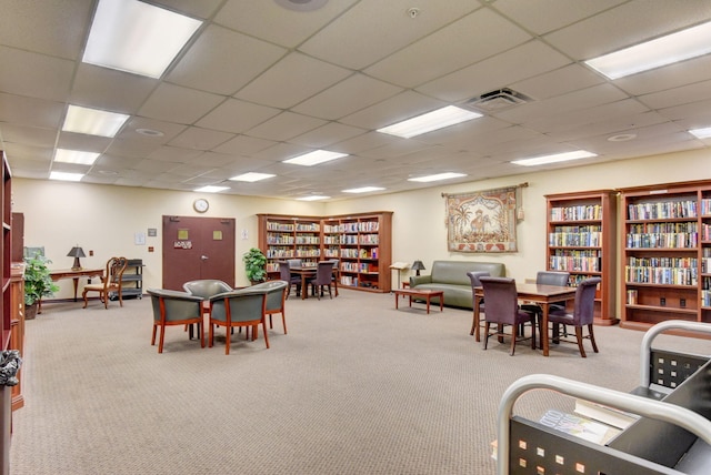 recreation room with light carpet and a drop ceiling