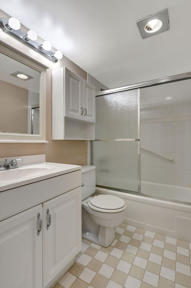 full bathroom featuring vanity, combined bath / shower with glass door, and toilet