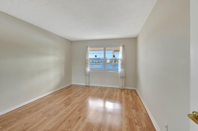 unfurnished room with a textured ceiling and light hardwood / wood-style floors