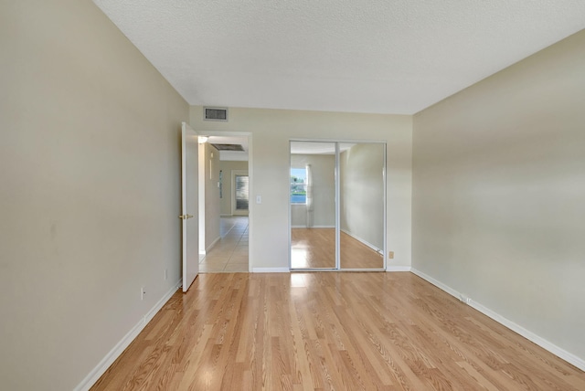 unfurnished bedroom featuring a closet, light hardwood / wood-style floors, and a textured ceiling