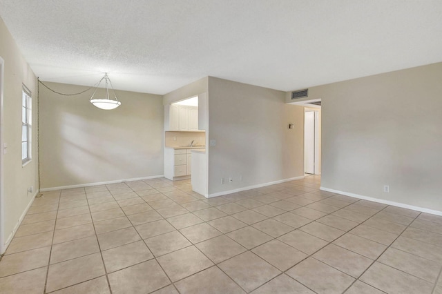 tiled empty room featuring sink and a textured ceiling