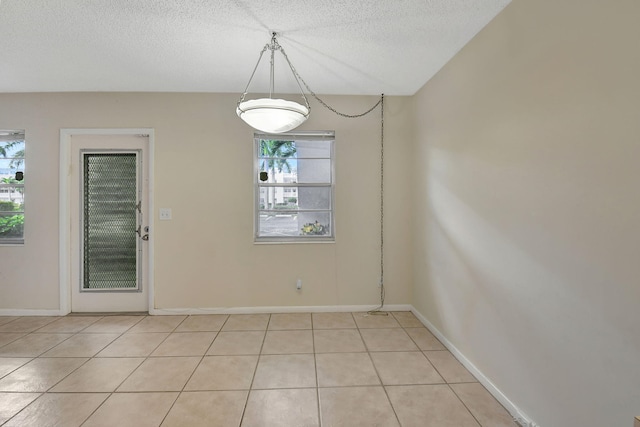 unfurnished dining area with a textured ceiling and light tile patterned flooring