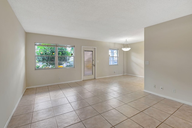 unfurnished room with a wealth of natural light, a textured ceiling, and light tile patterned floors