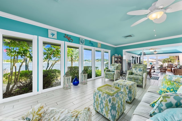 sunroom / solarium featuring a water view and ceiling fan