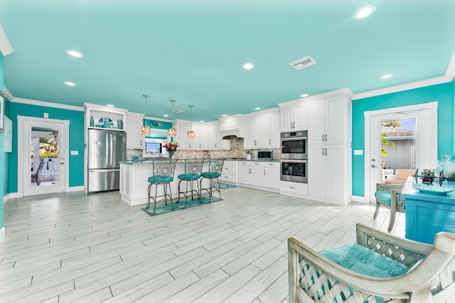 kitchen with appliances with stainless steel finishes, white cabinetry, decorative light fixtures, and tasteful backsplash