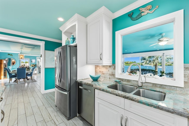 kitchen with ceiling fan, sink, white cabinets, appliances with stainless steel finishes, and backsplash