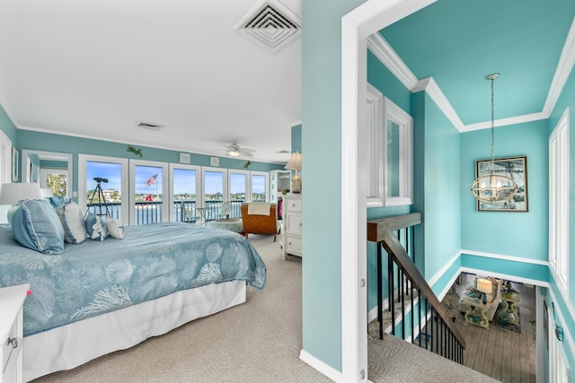 carpeted bedroom featuring crown molding and a chandelier