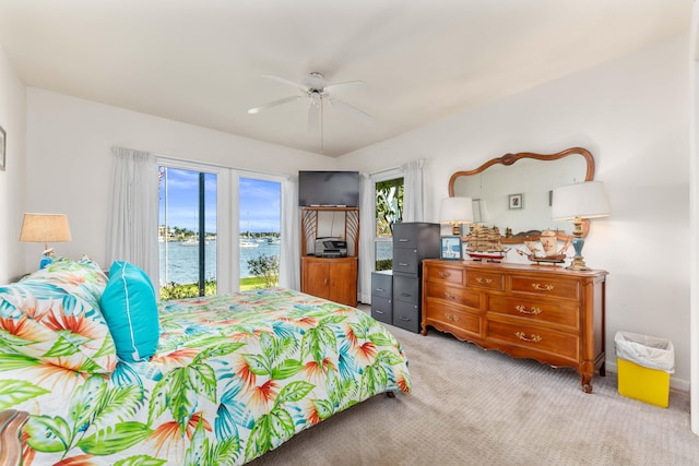 bedroom featuring a water view, light colored carpet, and ceiling fan