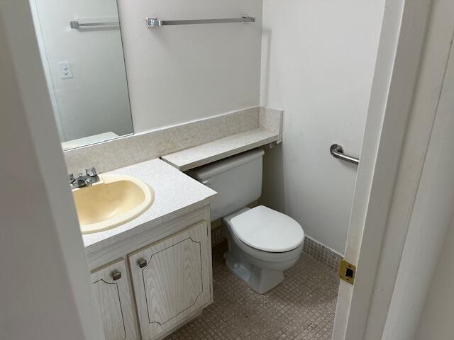 bathroom with toilet, tile floors, and vanity