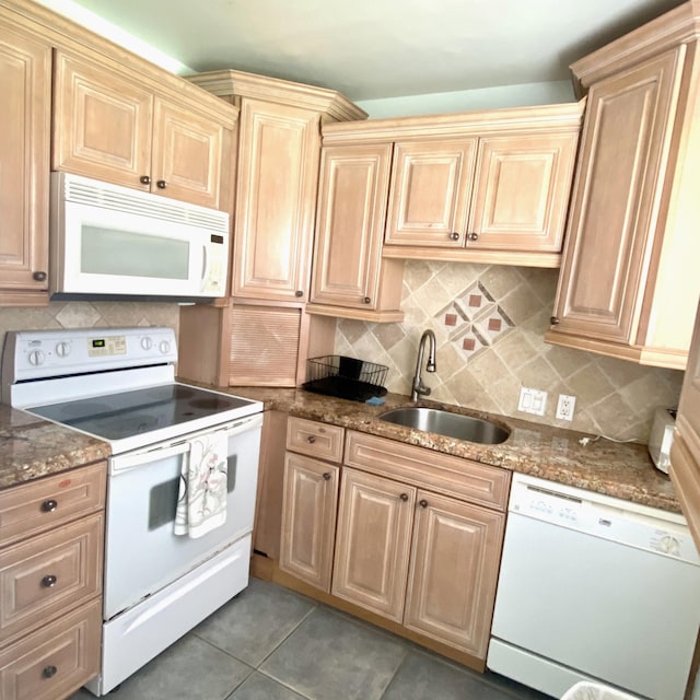 kitchen featuring white appliances, sink, dark stone counters, tile flooring, and tasteful backsplash