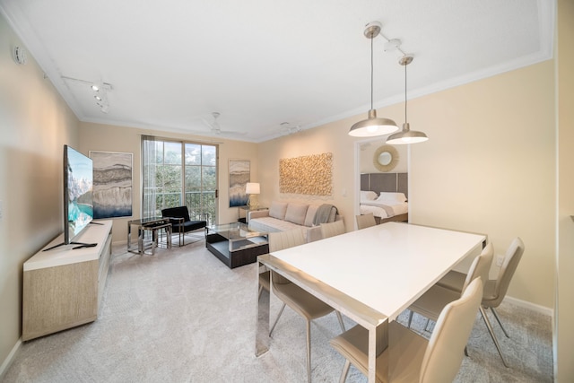 carpeted dining area featuring ornamental molding and rail lighting