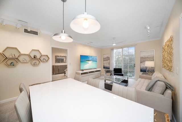 dining area with light carpet, rail lighting, and crown molding