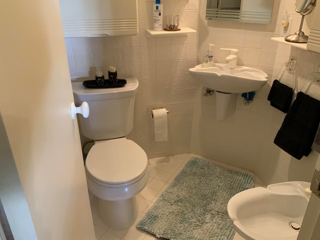 bathroom with toilet, tasteful backsplash, tile floors, and tile walls